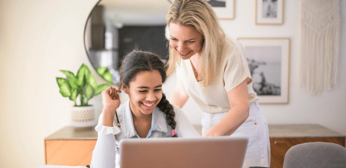 Una mujer y una niña colaboran en un ordenador portátil, inmersas en una productiva experiencia de aprendizaje en común.