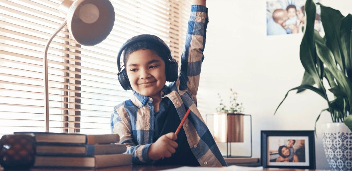 Un chico con auriculares está sentado en un escritorio, concentrado en su portátil, inmerso en su trabajo o entretenimiento.