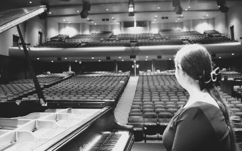 estudiante sentada al piano mirando al auditorio